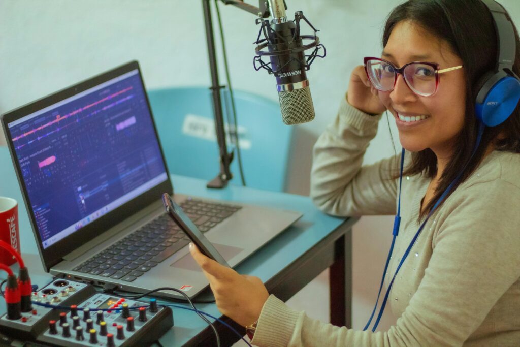 Smiling woman podcasting with professional microphone and laptop.