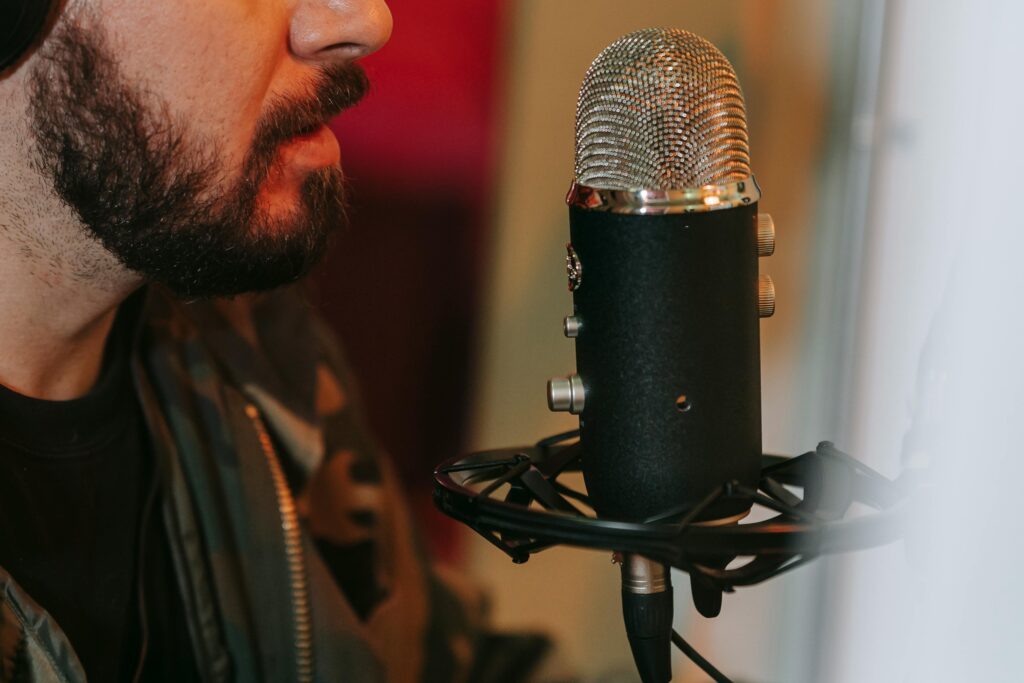 Close-up of a bearded musician singing into a professional microphone indoors.